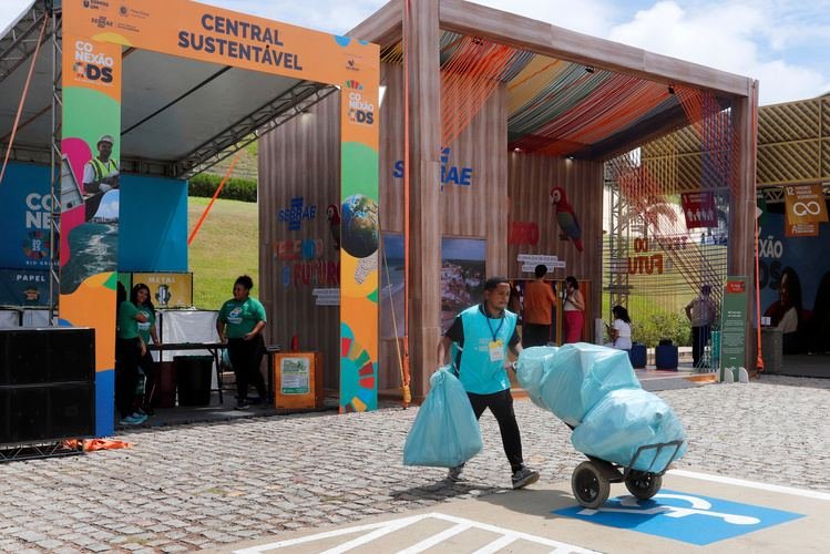 Central sustentável do evento com catador levando sacos de recicláveis